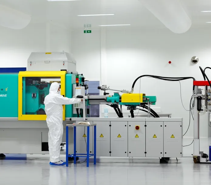 Operario en sala limpia trabajando con inyectora de silicona industrial